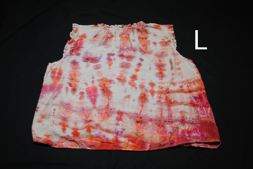 A sleeveless white top with a pink, orange, and purple tie-dye pattern, laid flat on a black background with a size label 'L' in the upper right.
