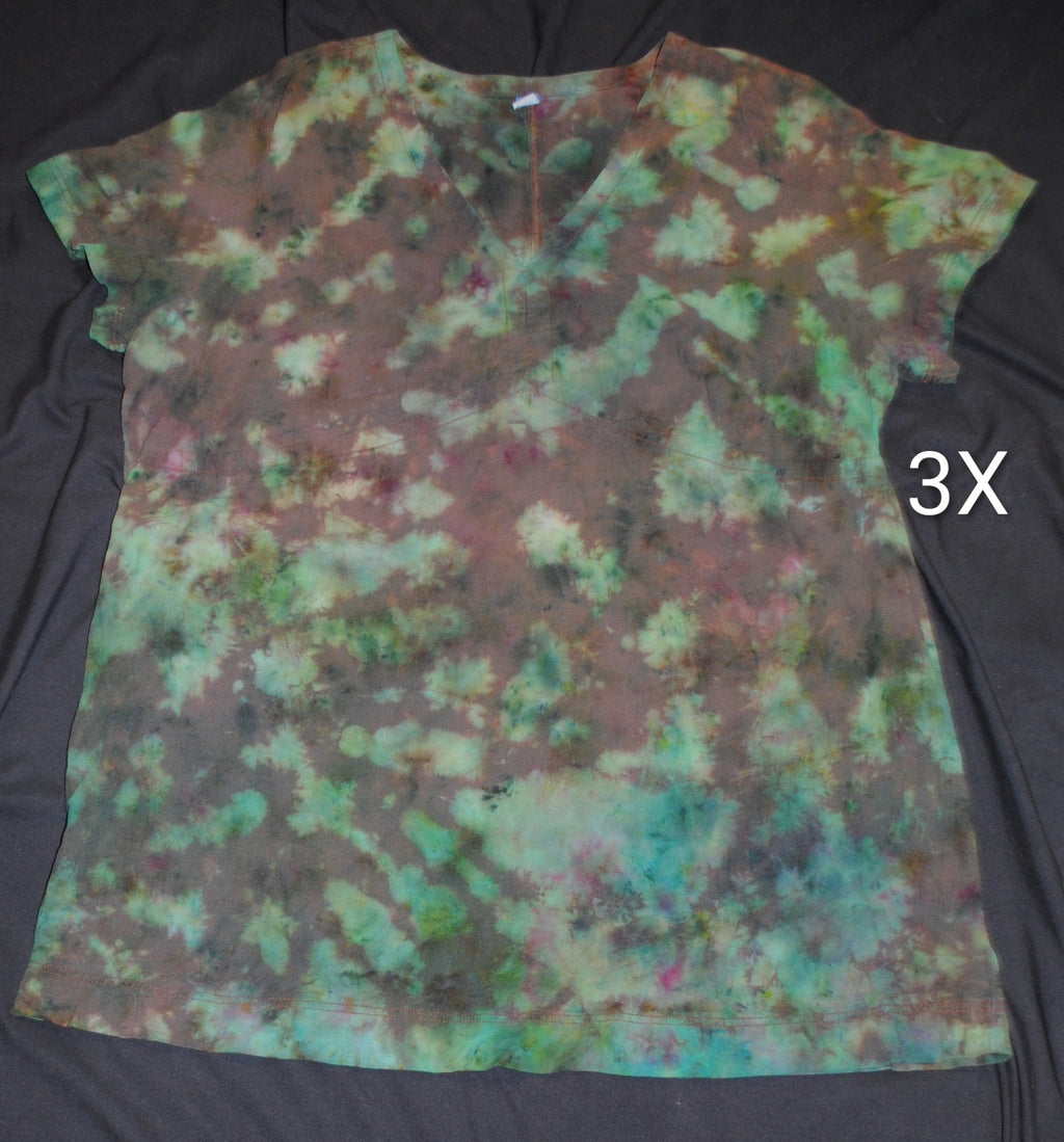 A short-sleeve tie-dye dress laid flat on a black fabric background, featuring a mottled pattern of teal, green, brown, and black. White letters '3X' is shown to the right of the dress.