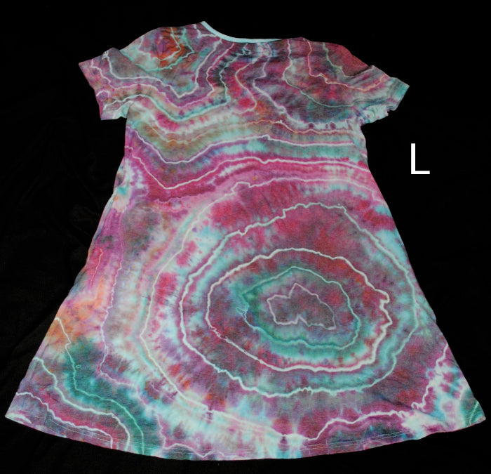 A short-sleeve A-line dress with a vibrant agate slice tie-dye pattern in pink, teal, and white, shown against a solid black background with a size label 'L' on the right.