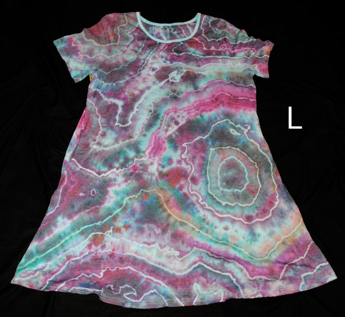 A short-sleeve A-line dress with a vibrant agate slice tie-dye pattern in pink, teal, and white, shown against a solid black background with a size label 'L' on the right.