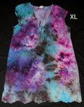 A sleeveless V-neck tie-dye top with eyelet embroidery, shown flat on a black background. The garment features a vibrant spiral tie-dye pattern in purple, pink, blue, and brown, with a scalloped hem.