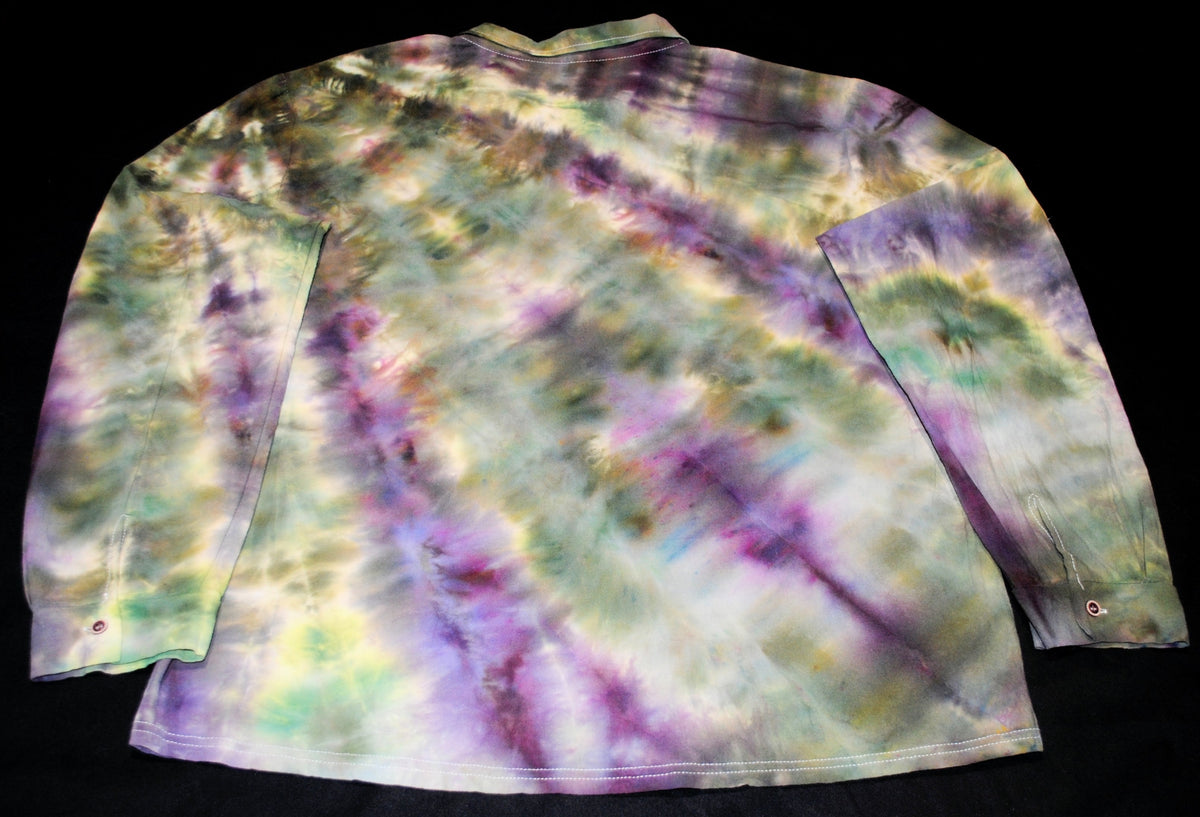 A long-sleeve tie-dye shirt laid flat against a black background, featuring a swirling pattern of purple, green, yellow, and white.