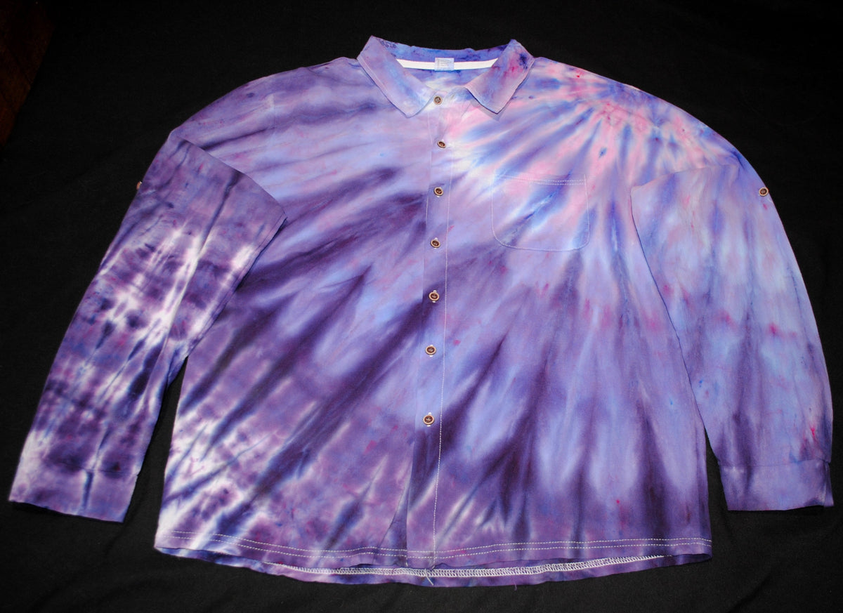 A long-sleeve button-up shirt with a purple, pink, and white tie-dye pattern, laid flat on a black background.