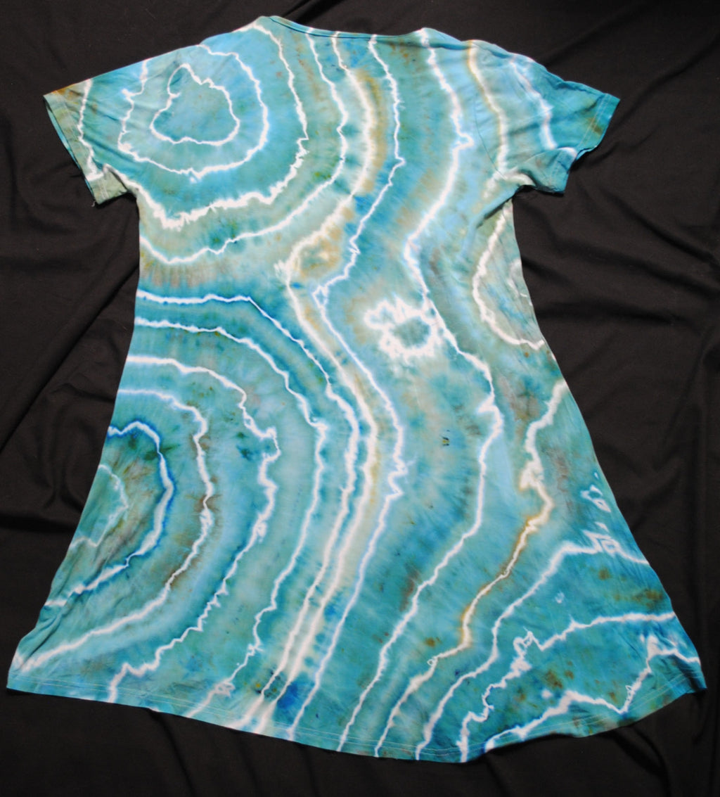 A short-sleeve tunic dress with a blue and white agate geode print, laid flat on a black fabric background.